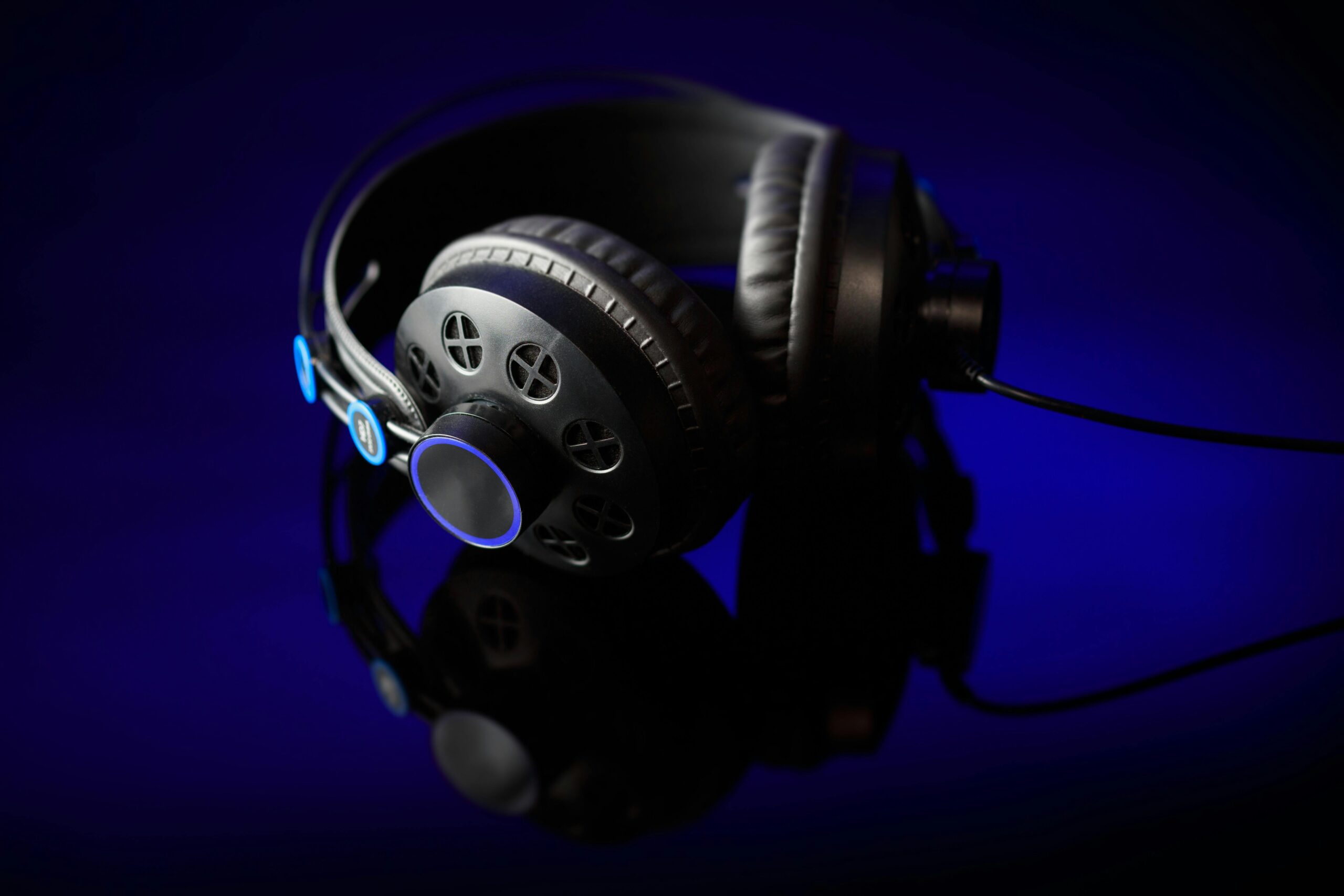 Stylish black headphones with glowing accents on a reflective surface against a dark backdrop.