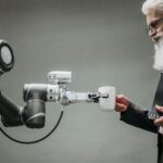 An elderly man receives a cup from a robotic arm in a modern office setting.